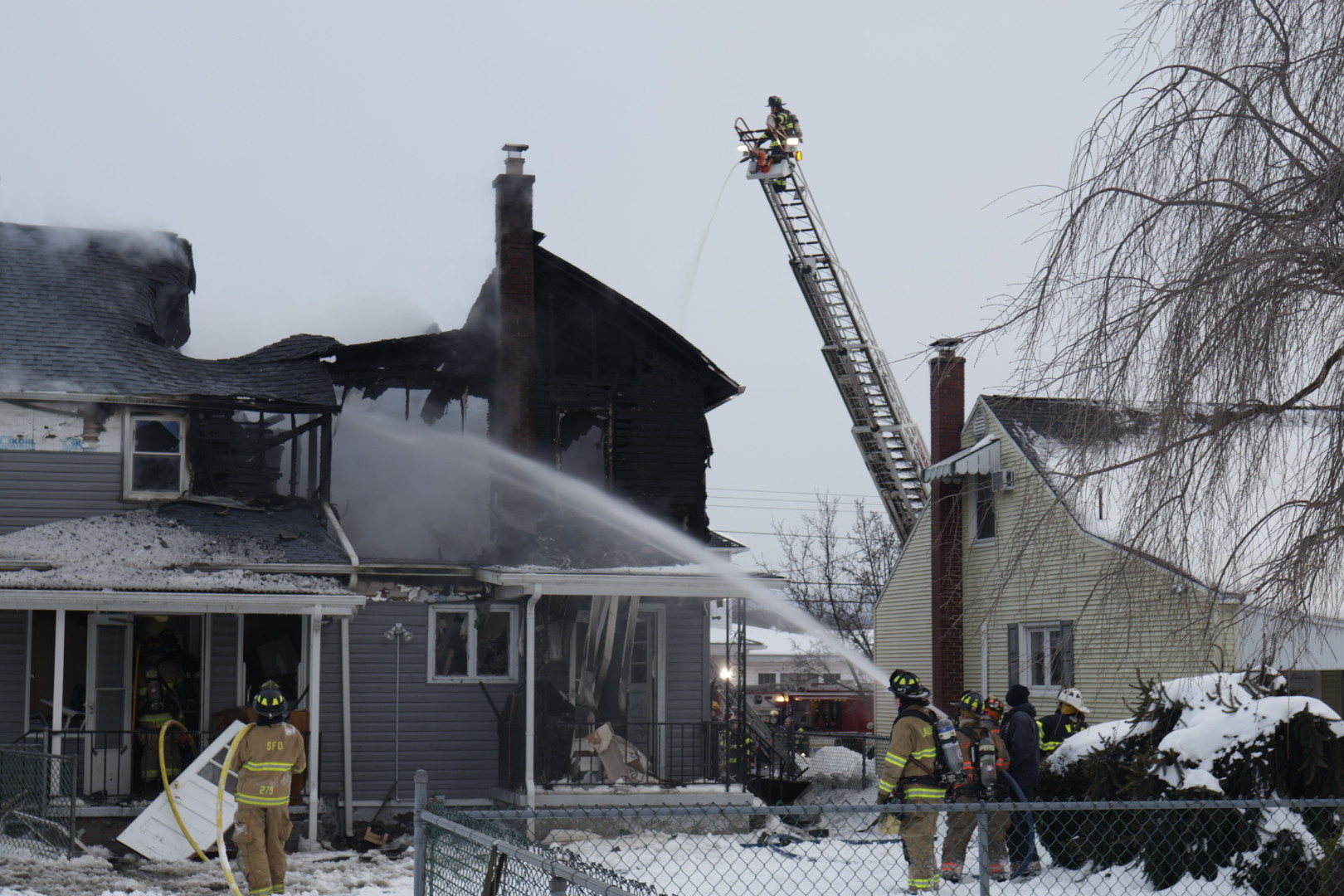 Firefighters battling a house fire during the day